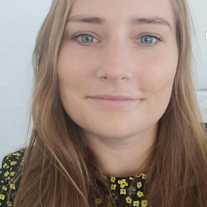 kvinde med langt brunt hår og en gul-blomstret trøje på