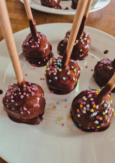 Billede af fem chokoladekugler på en hvid tallerken, med forskelligfarvet drys på
