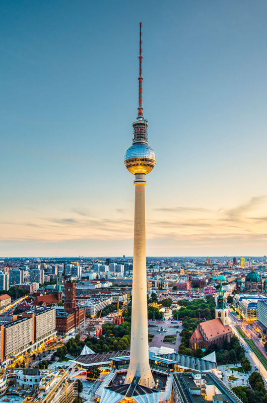 billede af tv-tårnet i Berlin. Højt tårn med en stor kugle næsten i toppen. Blå  og orange himmel  baggrunden.