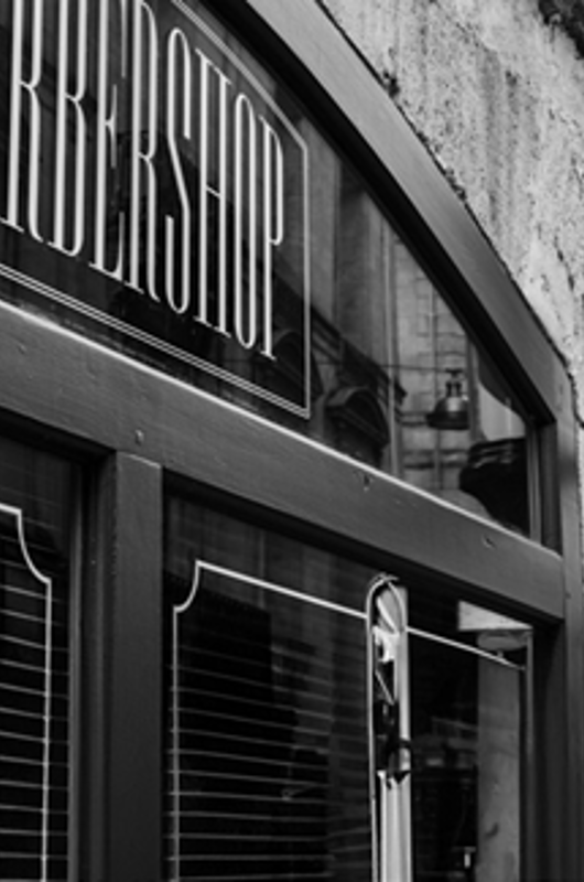 en barbarshop set ude fra. Røde mursten og et skilt hvor der står barbershop